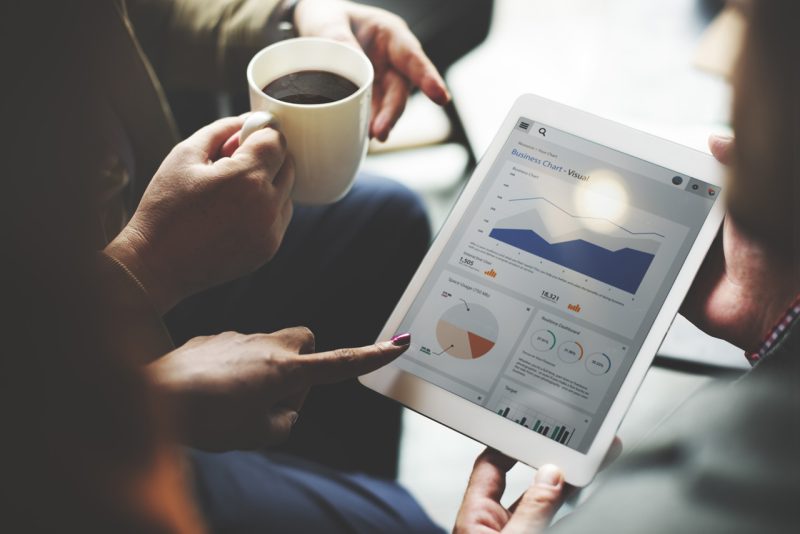 Tablet with Statistics Next to a Coffee Mug