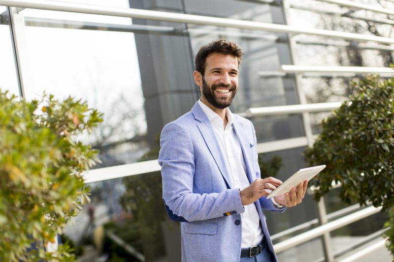 Smiling Man in Open Space with Tablet